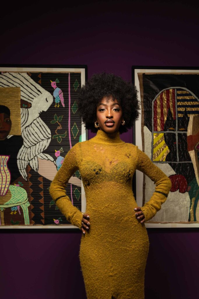 Ebony pose entre deux œuvres de l’artiste franco- camerounaise Manuèla Dikoumè : Autoportrait
au vase (1991) et Autoportrait au loup (1991)